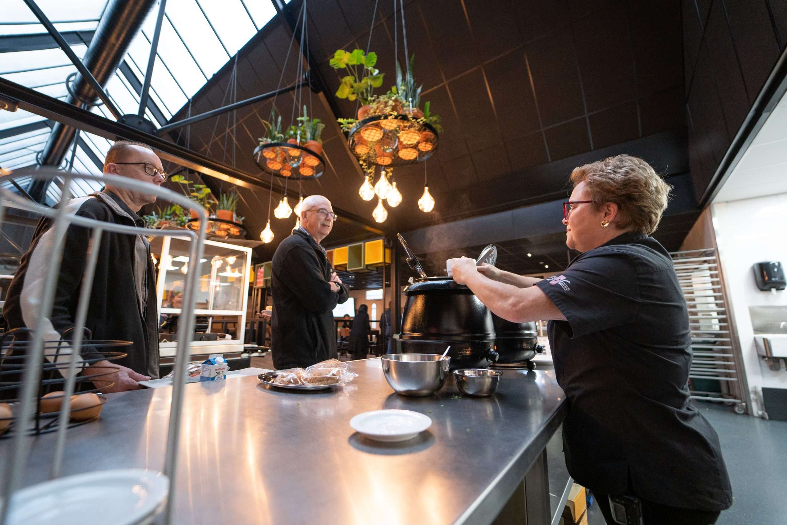 Medewerker soep aan het uitserveren in het bedrijfsrestaurant