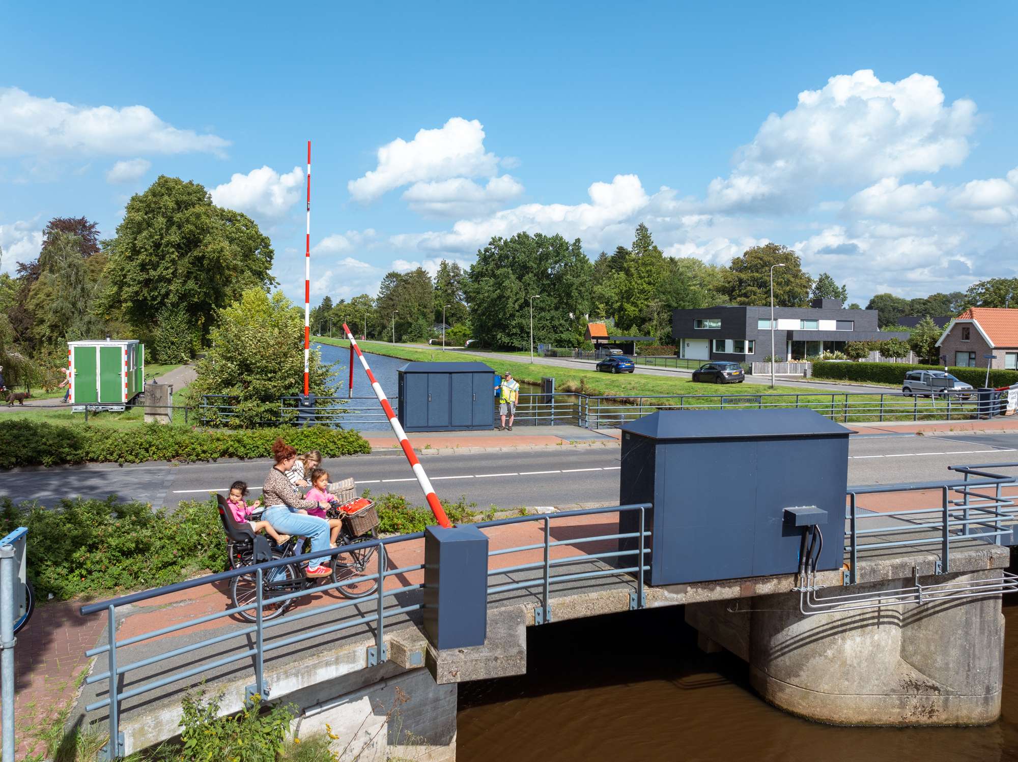 Moeder met kinderen op de fiets steken brug over