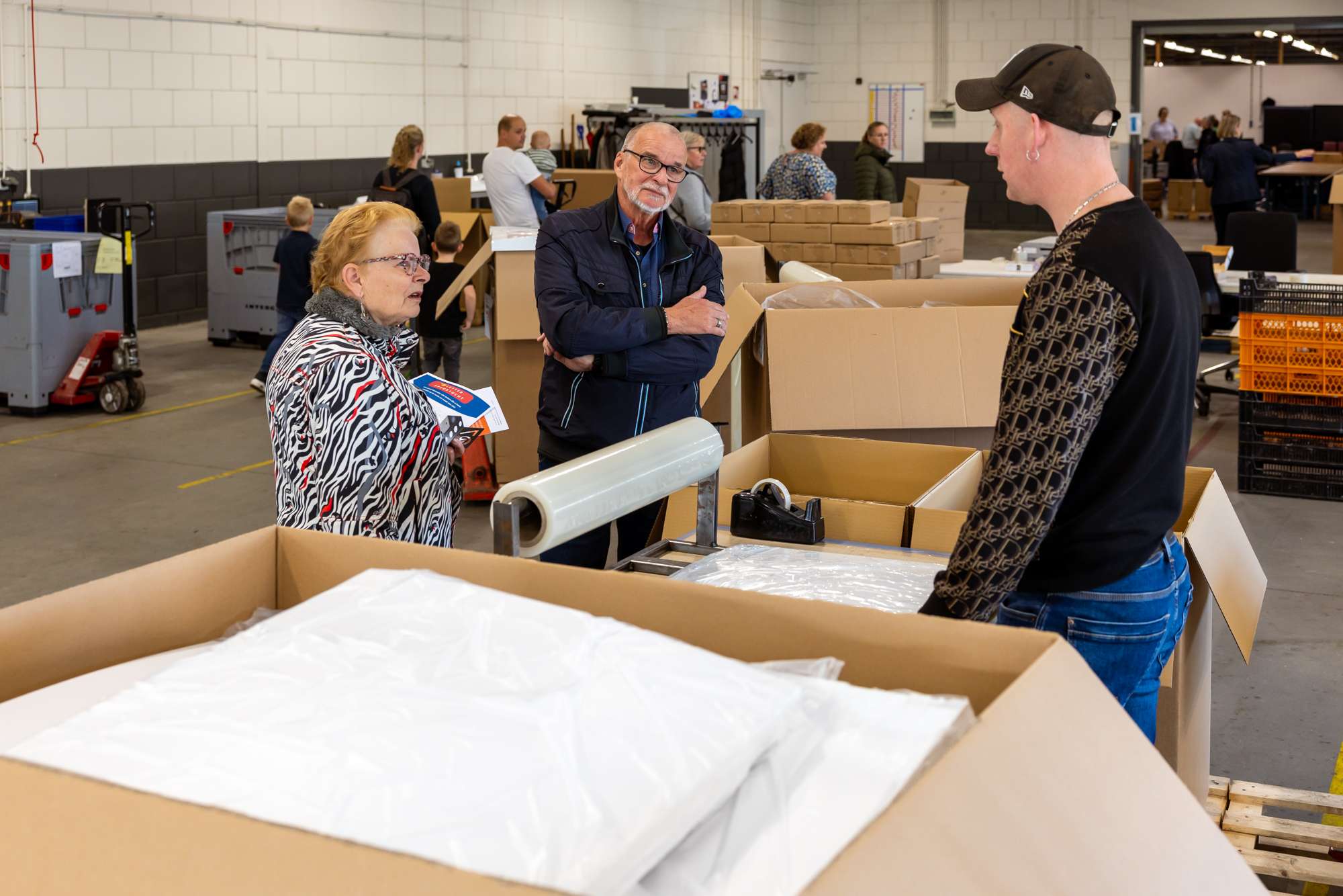 Twee bezoekers van open bedrijvendag krijgen uitleg van een medewerker