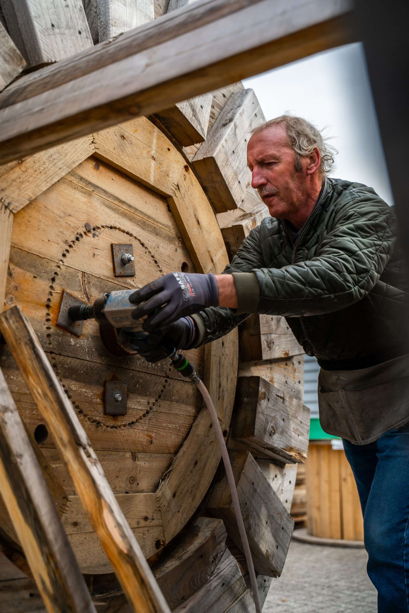 Man bezig met schroefmachine aan houten rad