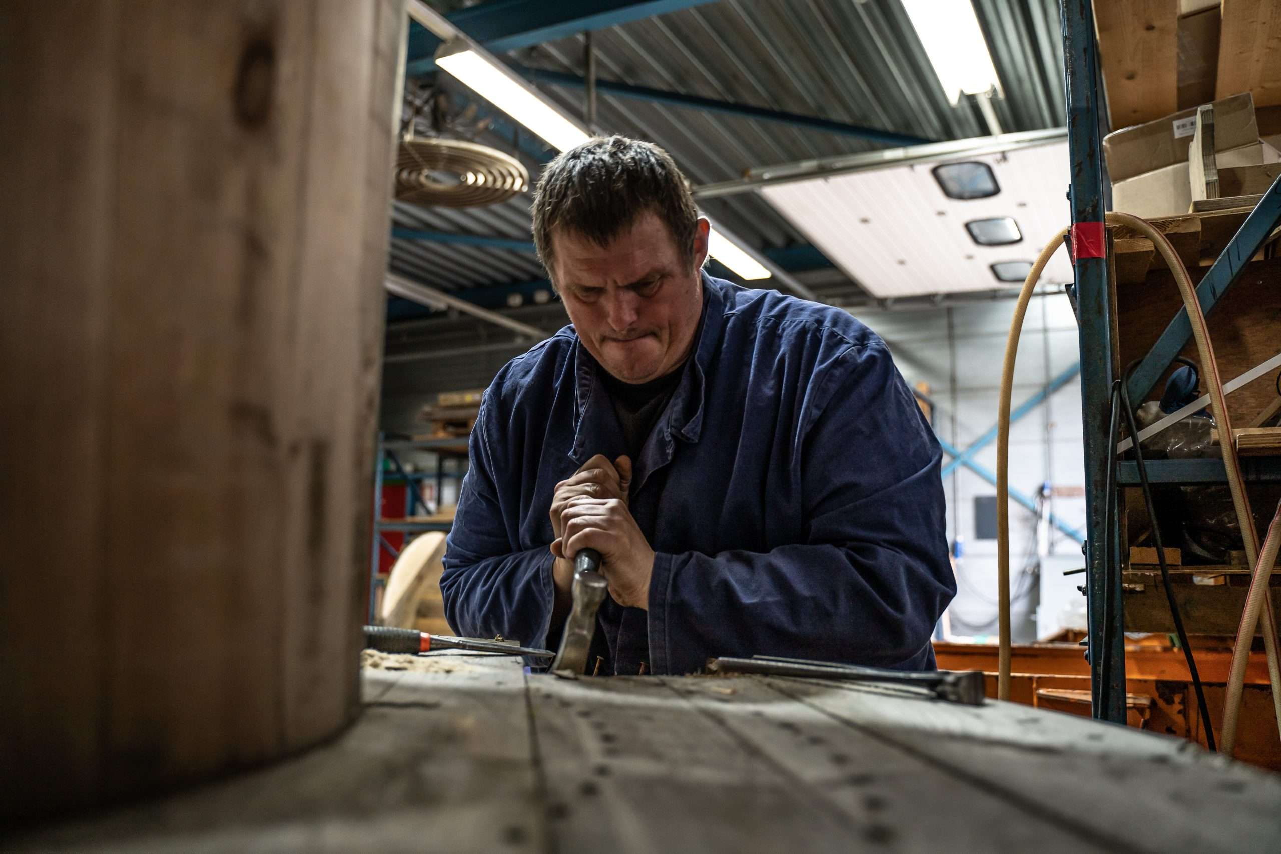 Man verwijdert spijkers uit plank met een hamer