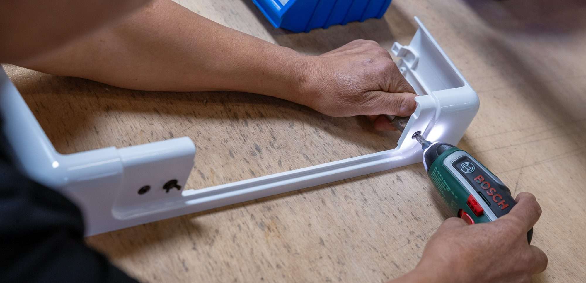 Iemand bezig met schroefmachine en een stuk plastic