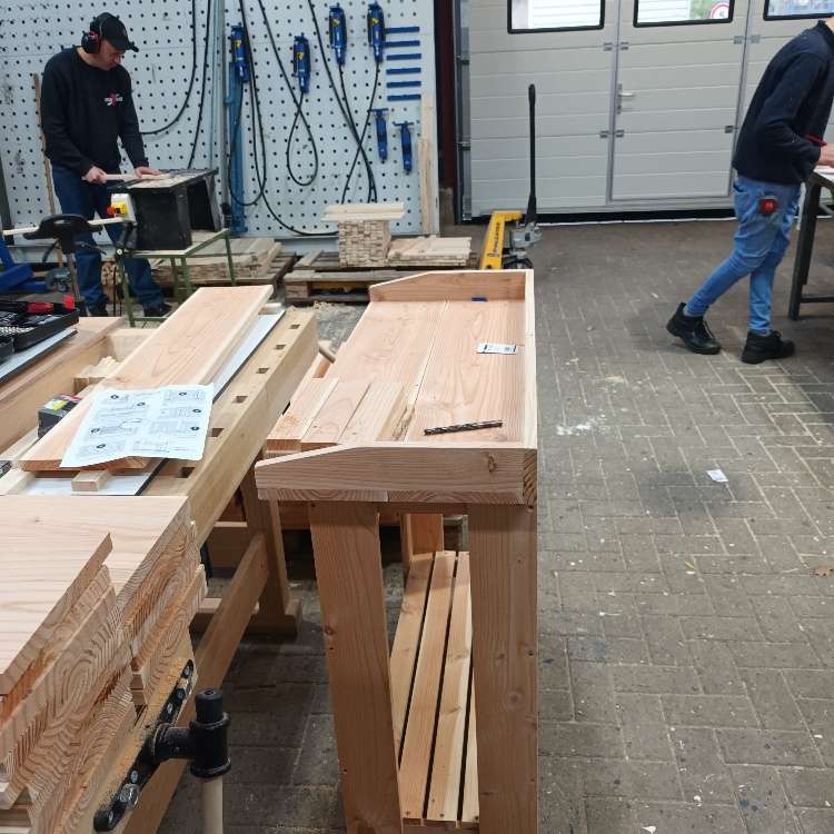 Medewerker aan het werk op de afdeling leerlijn hout, verschillende meubelstukken te zien